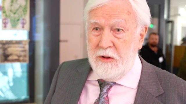 A photo of Green Party founder Michael Benfield, taken from a BBC interview. He has grey hair and a short grey beard.