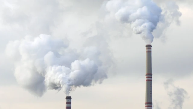 A photo of two industrial chimneys pumping out plumes of smoke.
