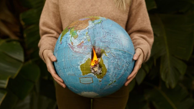 A photo of a person holding a large globe that has caught fire.