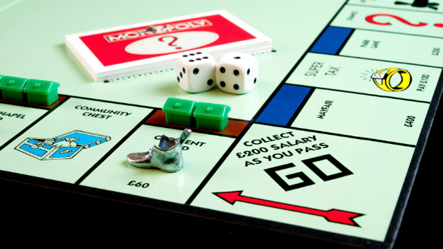 image showing a monopoly board on the 'Go' square, several pieces, dice and cards on the board