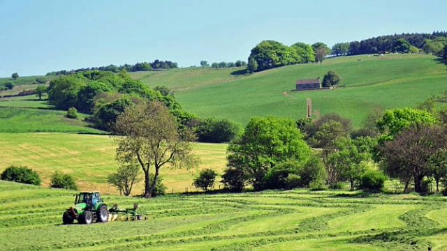 An image of the British countryside. Rolling green hills and a tractor in the foreground.