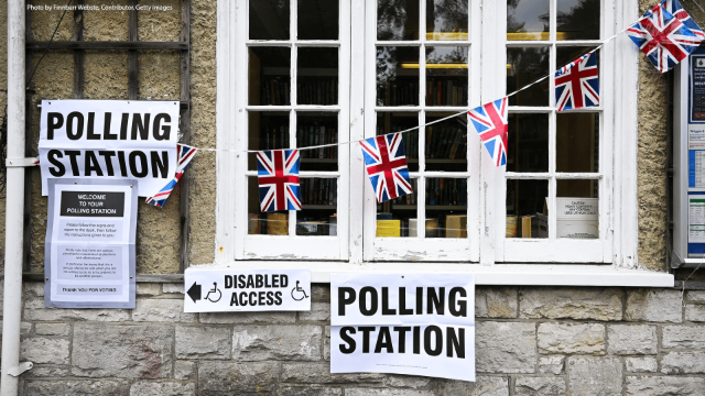 photograph (stock image) of a british polling station. stone walls, flags and signs hanging outside